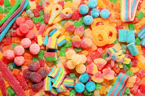 Assorted variety of sour candies includes extreme sour soft fruit chews, keys, tart candy belts and straws. 
Flat lay, sugar background concept for kids birthday party.